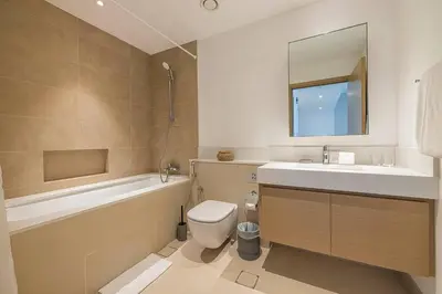 a bathroom with a sink toilet and a mirror at Daniels 1BR at Creek Horizon with Park View in Dubai