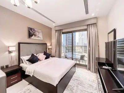 a bedroom with a bed and a tv and a balcony at Luton Vacation Homes - Elite Residence Downtown, Dubai in Dubai