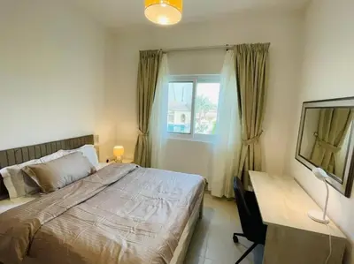 a bedroom with a bed and a desk and a window at Elite Inn: Amaranta75 (Townhouse Direct pool view) in Dubai