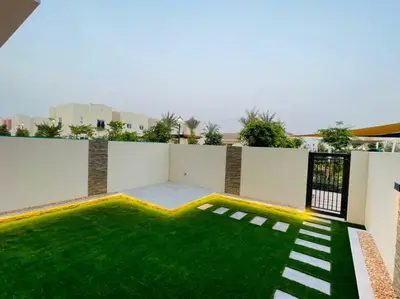 a backyard with a green lawn and a building at Elite Inn: Amaranta75 (Townhouse Direct pool view) in Dubai