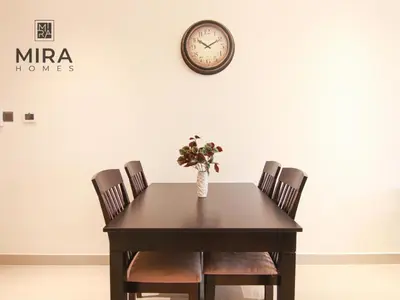 a table with chairs and a clock on a wall at Mira Holiday Homes - Lovely 1 bedroom apartment in Downtown in Dubai