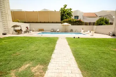 a backyard with a swimming pool and green grass at Comfortable Private Rooms in Compound Housing in Dubai
