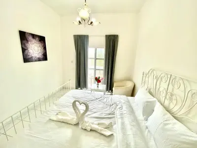 a bedroom with a white bed with two swans on it at Comfortable Private Rooms in Compound Housing in Dubai