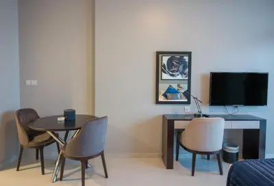 a living room with a table and chairs and a tv at Premium Studio with Beautiful Golf Course View in Dubai