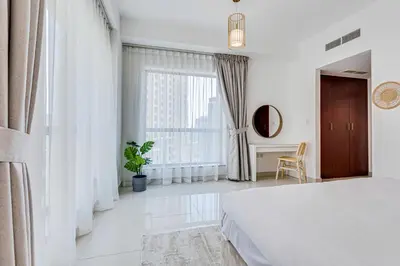 a white bedroom with a bed and a large window at 2 BD apartment in Bahar JBR in Dubai