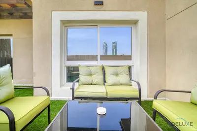 two chairs and a couch in a room with a window at Ornate 2BR at Diamond Views 1, Jumeirah Village Circle by Deluxe Holiday Homes in Dubai