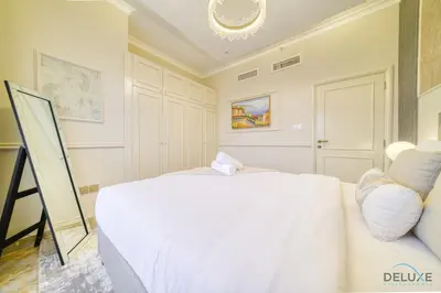 a bedroom with a white bed and a chair at Ornate 2BR at Diamond Views 1, Jumeirah Village Circle by Deluxe Holiday Homes in Dubai