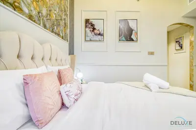 a white bed with pink and purple pillows on it at Ornate 2BR at Diamond Views 1, Jumeirah Village Circle by Deluxe Holiday Homes in Dubai
