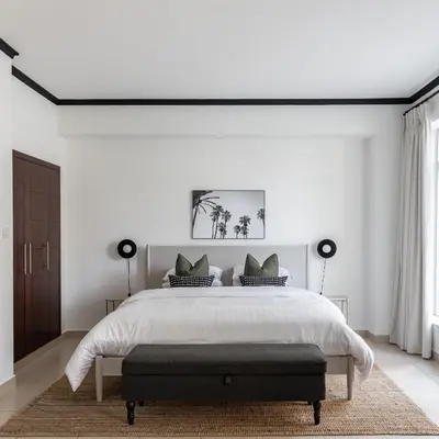 a white bedroom with a large bed with a bench at the end at Studio in Burj Views by Radiance Vacation Stays in Dubai