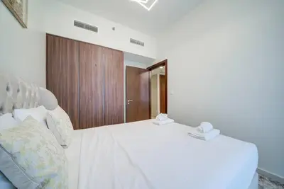 a bedroom with a white bed and a wooden cabinet at Classic Arabian Elegance with City Views in Dubai