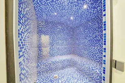 a bathroom with a blue tiled shower with a tub at Classic Arabian Elegance with City Views in Dubai