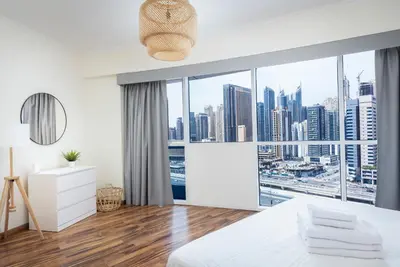 a white bedroom with a view of the city at 180° Sheik Zayed Road balcony views 2BR in JLT in Dubai