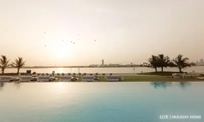 a swimming pool with a view of a body of water at LUX - The Elegant Palm Beach Suite in Dubai