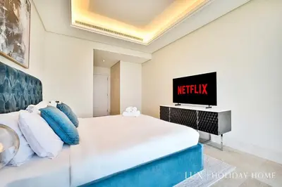 a bedroom with a bed and a tv on a wall at LUX - The Elegant Palm Beach Suite in Dubai