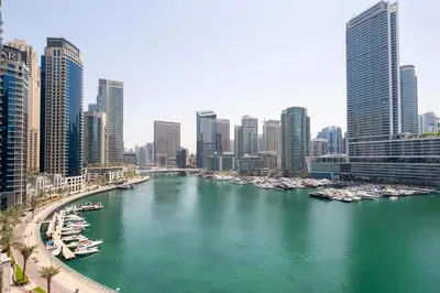a river with boats in a city with tall buildings at Frank Porter - The Point in Dubai