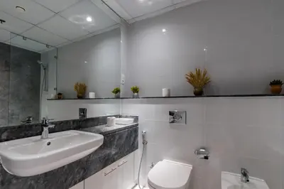 a bathroom with a sink and a toilet and a mirror at White Sage - Amna Tower in Dubai