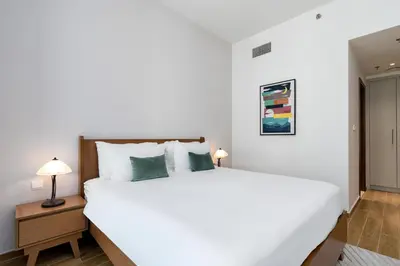 a bedroom with a large white bed and a lamp at White Sage - Amna Tower in Dubai