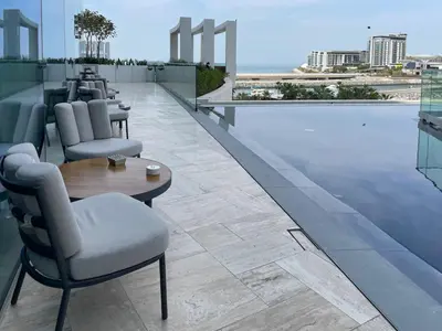 a hotel rooftop with a pool and tables and chairs at 72 floor 2BR at the Address JBR with Marina Views! in Dubai