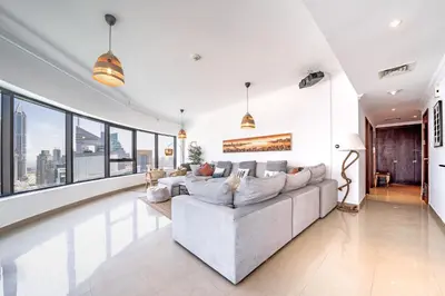 a living room with a large couch and large windows at Spacious 3BR with 180˚ Dubai Marina Views in Dubai
