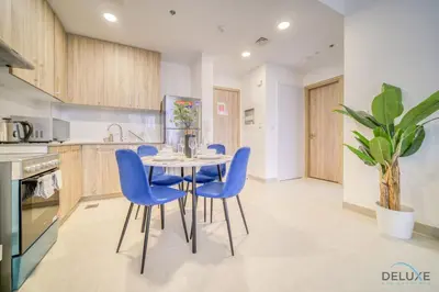 a kitchen with a table and blue chairs at Sophisticated 1BR at Town Square Rawda Dubailand by Deluxe Holiday Homes in Dubai