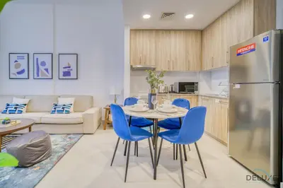 a kitchen and living room with a table and blue chairs at Sophisticated 1BR at Town Square Rawda Dubailand by Deluxe Holiday Homes in Dubai