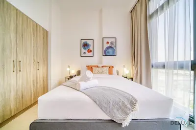 a bedroom with a white bed and a large window at Sophisticated 1BR at Town Square Rawda Dubailand by Deluxe Holiday Homes in Dubai
