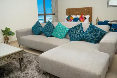 a living room with a couch and blue pillows at Luxury Casa - Platinum Sea View Apartment 2BR at JBR Beach in Dubai