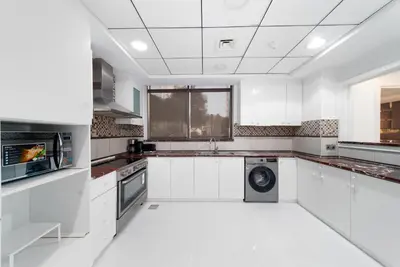 a white kitchen with a washing machine in it at Elan Suites 5-Bedroom Beach Villa in Dubai
