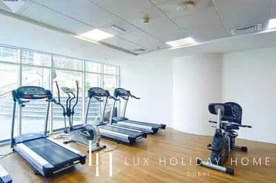 a gym with several tread machines in a room at LUX Marina View Prime Location Near Beach in Dubai