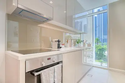 a white kitchen with a stove and a window at Studio with City Views, Jumeirah Lake Towers - Mint Stay in Dubai