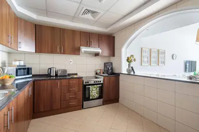 a large kitchen with wooden cabinets and an archway at Frank Porter - Grand Horizon in Dubai