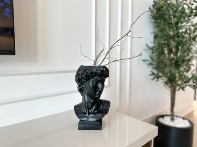 a bust of a woman sitting on a table next to a plant at Stylish 2 Bedroom Dior-Inspired Apartment Connected to Dubai Mall in Dubai