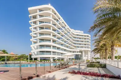 a large white building with a swimming pool and palm trees at GlobalStay Azizi Mina Beachfront Apartments Palm Jumeirah in Dubai
