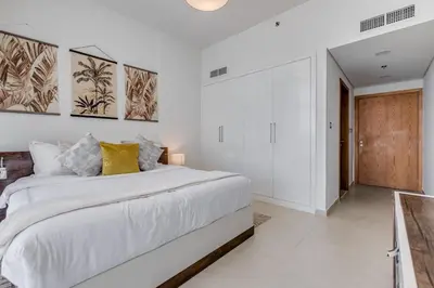 a white bedroom with a large bed with yellow pillows at GlobalStay Azizi Mina Beachfront Apartments Palm Jumeirah in Dubai