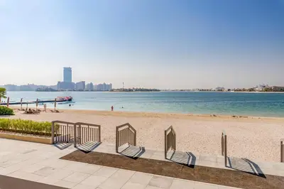 a row of chairs on a beach next to the water at GlobalStay Azizi Mina Beachfront Apartments Palm Jumeirah in Dubai