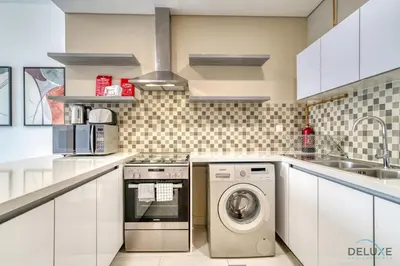a kitchen with a washing machine and a sink at Deal of the Week Stylish 1BR with Partial Burj Views by Deluxe Holiday Homes in Dubai