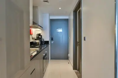 a hallway leading to a kitchen with a blue door at HiGuests - Roomy and Chic Studio with Panoramic Canal Views in Dubai