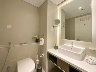 a bathroom with a sink and a toilet and a mirror at HiGuests - Roomy and Chic Studio with Panoramic Canal Views in Dubai