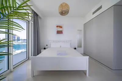 a white bedroom with a white bed and a large window at Breathtaking Atlantis view, Spacious 2BR on beach in Dubai