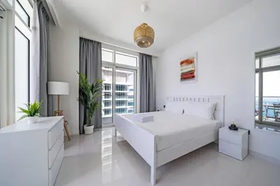 a white bedroom with a large white bed and windows at Breathtaking Atlantis view, Spacious 2BR on beach in Dubai