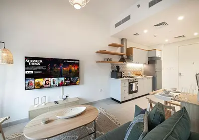 a living room with a table and a kitchen at First Class Apartments in Dubai Hills - Next to Dubai Hills Mall - Socio, Collective and Golfville Towers in Dubai
