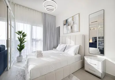 a white bedroom with a large bed and a mirror at First Class Apartments in Dubai Hills - Next to Dubai Hills Mall - Socio, Collective and Golfville Towers in Dubai