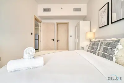a white bedroom with a large white bed and a door at Harmonious 1BR at Binghatti Avenue Al Jaddaf by Deluxe Holiday Homes in Dubai