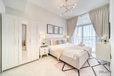 a white bedroom with a bed and a window at Harmonious 1BR at Binghatti Avenue Al Jaddaf by Deluxe Holiday Homes in Dubai