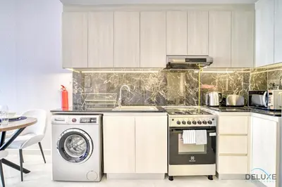 a kitchen with a stove and a washing machine at Harmonious 1BR at Binghatti Avenue Al Jaddaf by Deluxe Holiday Homes in Dubai
