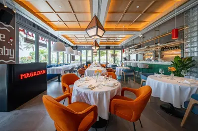 a restaurant with white tables and orange chairs at Radisson Beach Resort Palm Jumeirah in Dubai