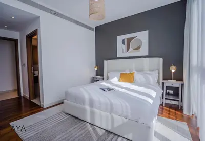 a bedroom with a white bed and a gray wall at Luxury Apartment with Pool, Patio & Gym in City Walk By ĀYA Boutique in Dubai