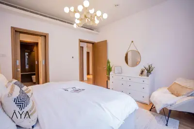 a bedroom with a white bed and a dresser and a mirror at Luxury Apartment with Pool, Patio & Gym in City Walk By ĀYA Boutique in Dubai