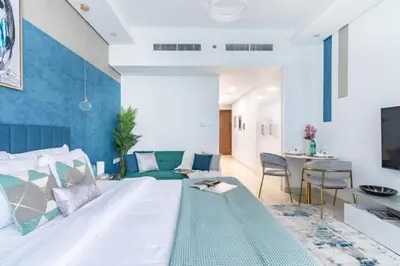 a bedroom with a bed and a living room at The Smart Concierge - Waves by Kasco in Dubai