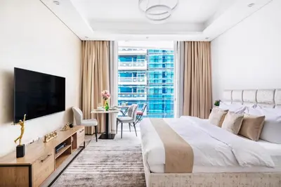 a bedroom with a large bed and a tv at The Smart Concierge - Waves by Kasco in Dubai